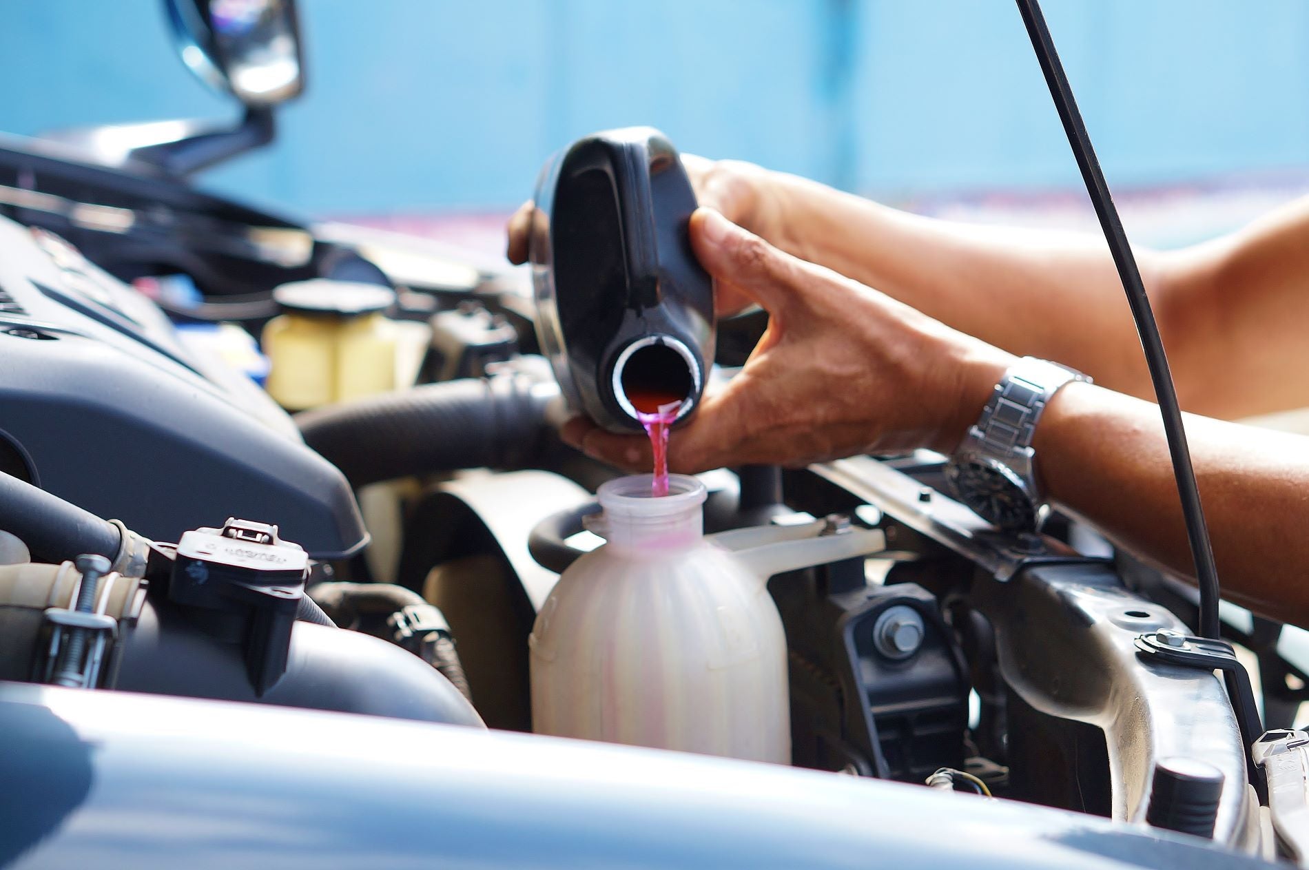 Mechanic Adding OAT coolants and antifreeze protection to prevent engine overheat.